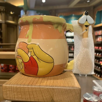 Winnie the Pooh, bal kapaklı bir kupadan ve Disneyland'daki seramik bir kupadan bir bardak su içiyor